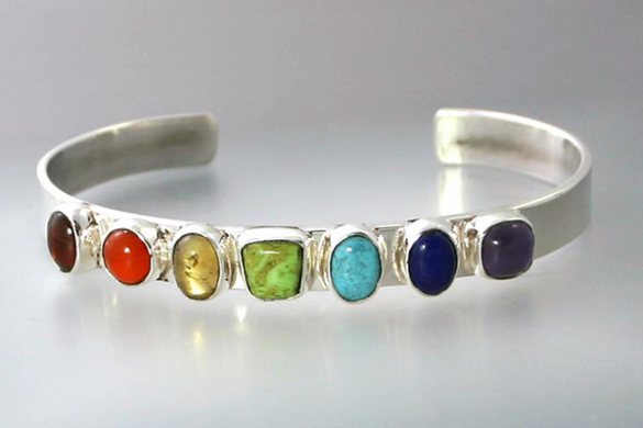 a silver rainbow bracelet by jocelyn hunter jewelry that represents the chakras and lgbt+ community. The stones are garnet, gaspeite, amethyst, carnelian, citrine, turquoise, and lapis lazuli.
